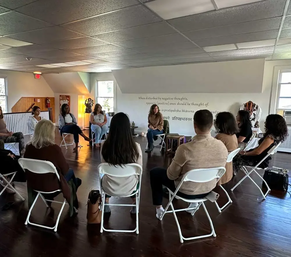 A small intimate grief support group seated in a circle with a candle at the center in Saddle River NJ